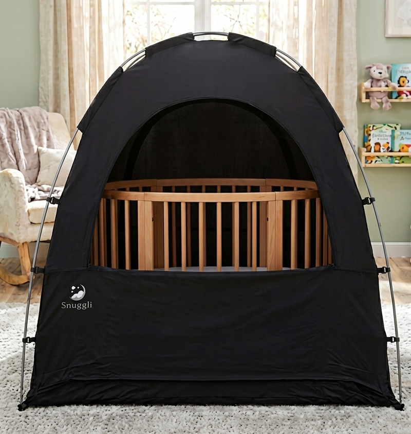 Black baby sleep tent with a crib inside, placed in a room with curtains and toys.